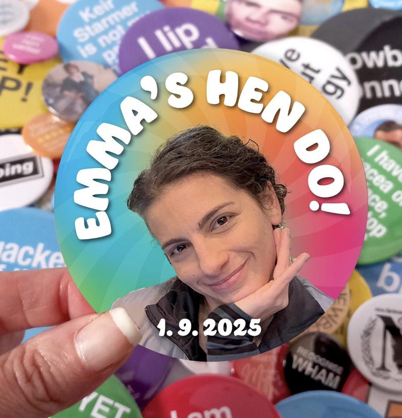 May include: A circular pin-back button featuring a rainbow-colored radial background. The text "EMMA'S HEN DO!" is printed in white along the top curve, and the date "1.9.2025" is printed in white at the bottom. A photograph of a person is centered.