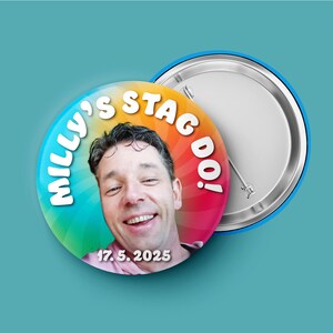 May include: A circular pin-back button featuring a colorful rainbow sunburst background. The button displays a photograph of a smiling person, the text "MILLY'S STAG DO!" in white letters, and the date "17. 5. 2025" printed at the bottom.