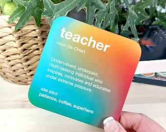 May include: A colorful square card with the word "teacher" in white text. The card defines a teacher as an undervalued, underpaid, multi-tasking individual who inspires, motivates, and educates under extreme pressure. The card also lists patience, coffee, and superhero as related terms.