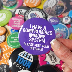 May include: Purple button with white text that reads "I have a compromised immune system. Please keep your distance."