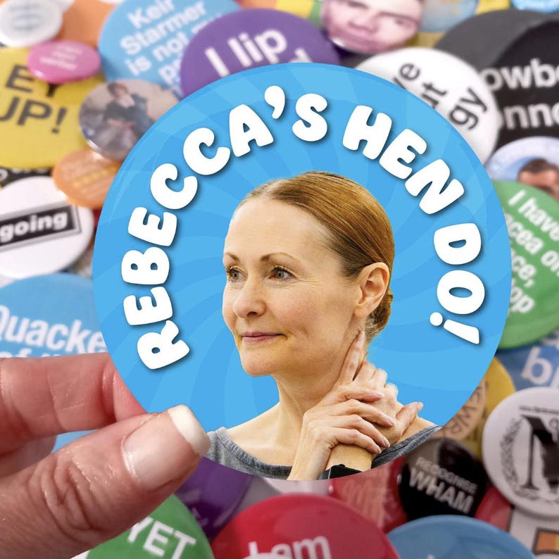 May include: A circular button featuring a light blue background with a swirling pattern and the white text "REBECCA'S HEN DO!". The center of the button displays a photographic portrait of a person with light brown hair looking to the side.