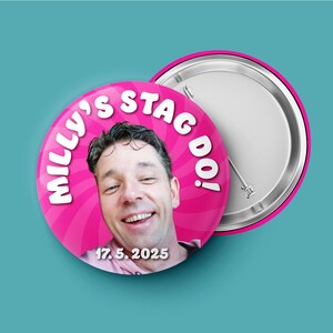 May include: A round pin-back button featuring a photograph of a smiling person. The background is a bright pink radial pattern with the white text "MILLY'S STAG DO!" arched at the top and the date "17. 5. 2025" printed in white at the bottom.