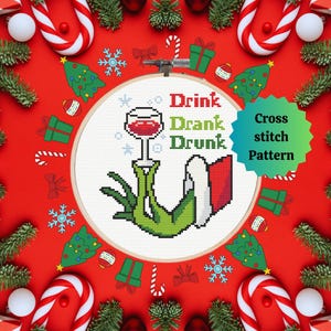 Puede incluir: Un patrón de punto de cruz con un personaje verde sosteniendo una copa de vino, con las palabras "Drink Drank Drunk". El diseño está rodeado de decoraciones navideñas sobre un fondo rojo, incluyendo bastones de caramelo, adornos y pequeños árboles de Navidad.