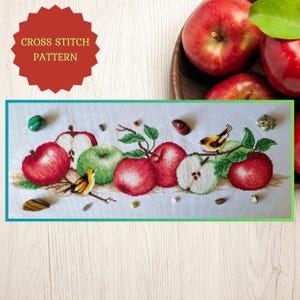 May include: Cross stitch pattern of a still life with red apples, green apples, and a small yellow bird. The pattern is surrounded by small stones and crystals.