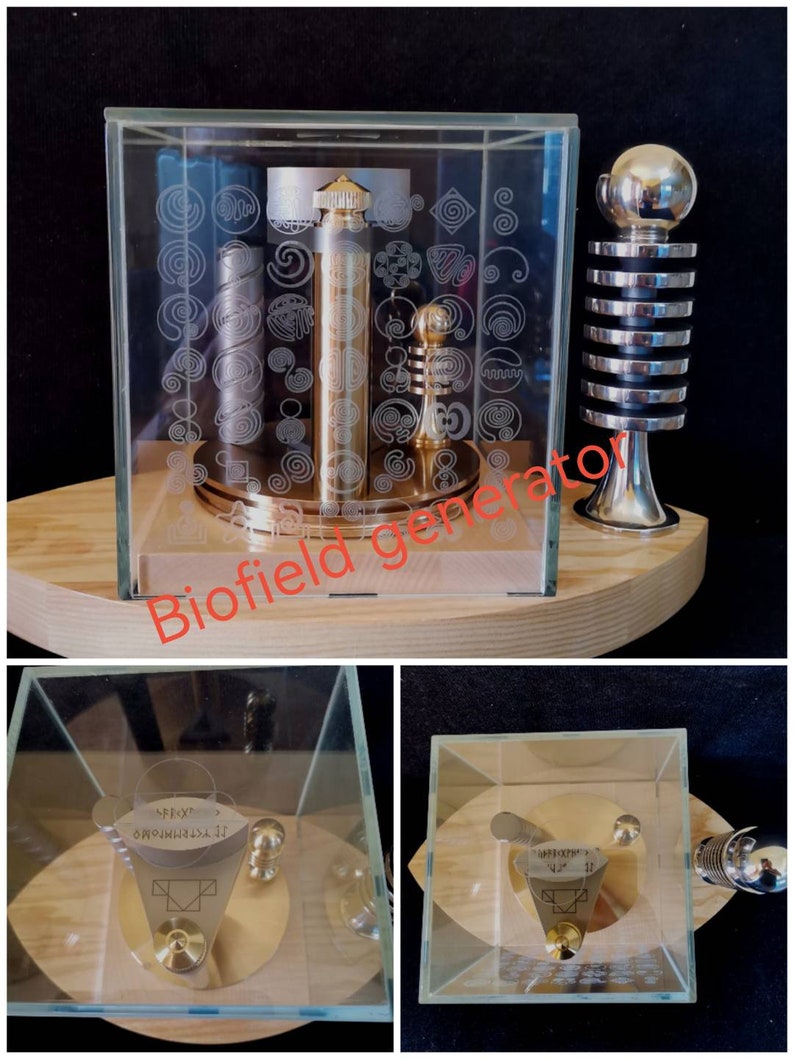 Pu&ograve; includere: Un generatore di biocampo dorato in un cubo di vetro su una base di legno. Il generatore ha un design a spirale ed &egrave; circondato da spirali pi&ugrave; piccole. La base ha le parole "Biofield Generator" scritte su di essa.