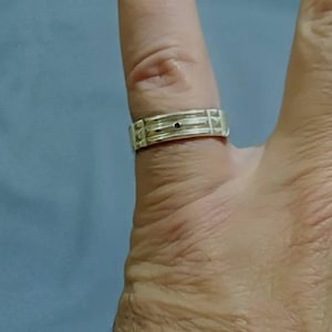 Pu&ograve; includere: Un anello a fascia d'argento con una piccola pietra nera al centro.