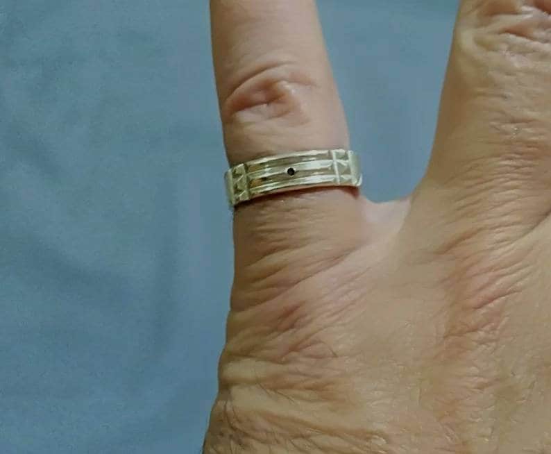 Pu&ograve; includere: Un anello a fascia d'argento con una piccola pietra nera al centro.