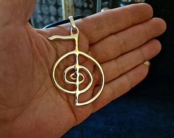May include: Silver pendant necklace featuring a large, intricate, circular design with a smaller circle inside. The design is similar to a yin yang symbol.