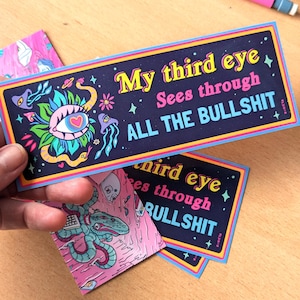 May include: Two colourful stickers with a psychedelic design. The top sticker has a blue background with a pink and green eye, a snake, and stars. The text reads "My third eye sees through all the bullshit". The bottom sticker has a pink background with an octopus and the text "third eye sees through BULLSHIT".