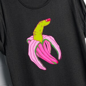May include: A black t-shirt with a graphic of a green finger with pink nail polish, inside a pink banana peel.