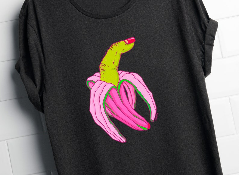 May include: A black t-shirt with a graphic of a green finger with pink nail polish, inside a pink banana peel.