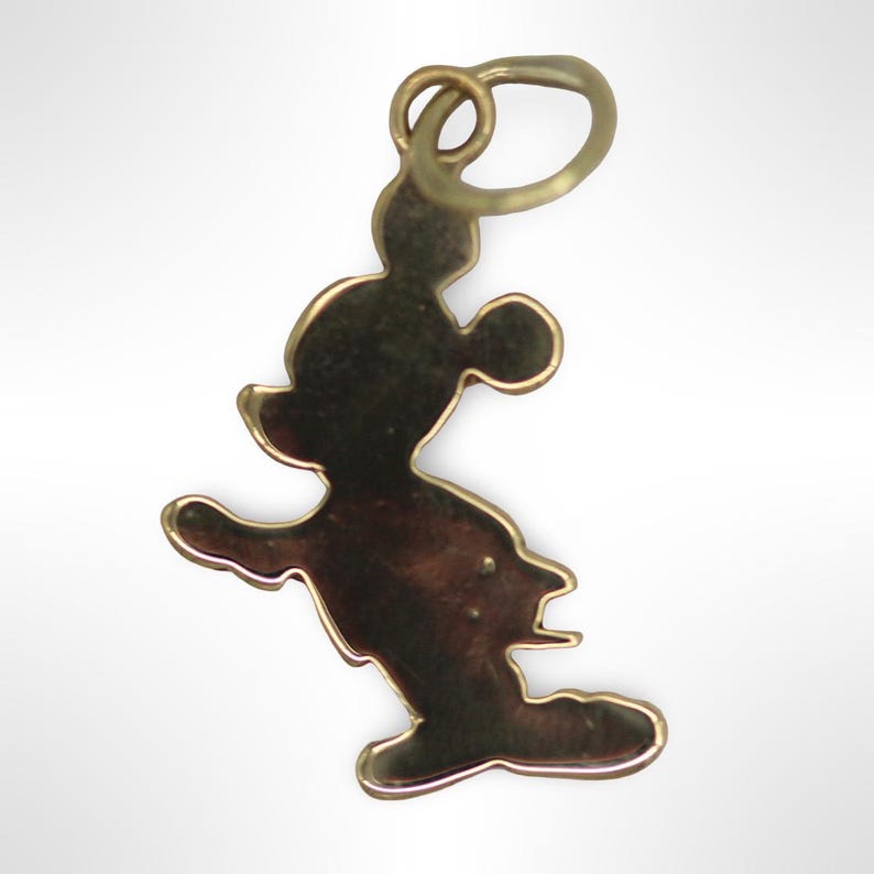 Puede incluir: Un dije de Mickey Mouse de color dorado. El dije es una silueta de Mickey Mouse con un bucle en la parte superior para sujetarlo a una cadena o pulsera.