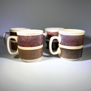 May include: Set of four brown and white striped ceramic coffee mugs with a textured design.