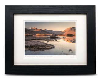 May include: A framed photograph of a lake with mountains in the background. The lake is calm and reflects the mountains and sky. The text "An Monadh Ruadh and Loch nan  A' -Mhachair" is printed below the image.
