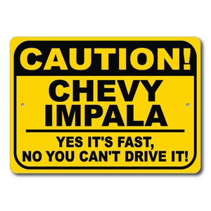 以下が含まれることがあります： 「注意！CHEVY IMPALA」と黒い文字で書かれた黄色の長方形の看板。 「YES IT'S FAST, NO YOU CAN'T DRIVE IT!」と書かれています。 看板は角が丸く、取り付け用の小さな穴が2つあります。
