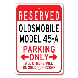 May include: Red and white sign with the text "RESERVED OLDMOBILE MODEL 45-A PARKING ONLY" with arrows pointing left and right. The text "ALL OTHERS WILL BE SOLD FOR SCRAP" is below the arrows.