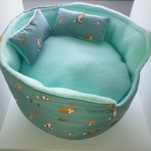 May include: A light blue pet bed with a removable cushion. The bed is made of soft fabric and features a fox print. The cushion is also light blue and has a fox print.