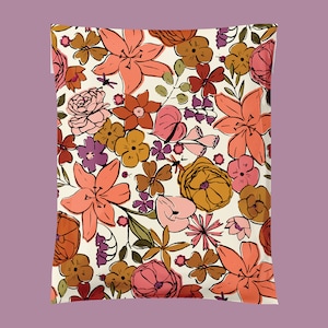 May include: A floral pattern featuring a variety of flowers in shades of peach, orange, brown, and purple against an off-white background. The design includes lilies, roses, and other stylized blooms, creating a vintage, botanical aesthetic.