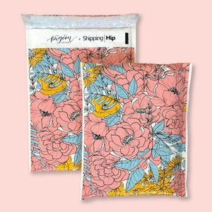 May include: Two white padded mailing envelopes with a floral pattern. The pattern features pink, yellow, and blue flowers on a white background. The envelopes have the text "The Pigeon Letters x Shipping | Hip" printed on the front.
