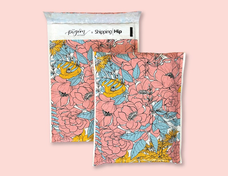 May include: Two white padded mailing envelopes with a floral pattern. The pattern features pink, yellow, and blue flowers on a white background. The envelopes have the text "The Pigeon Letters x Shipping | Hip" printed on the front.