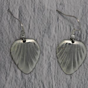 Op de afbeelding: Een paar zilveren oorbellen met een bladvormig ontwerp. De oorbellen hebben een getextureerd oppervlak en een eenvoudige haaksluiting.