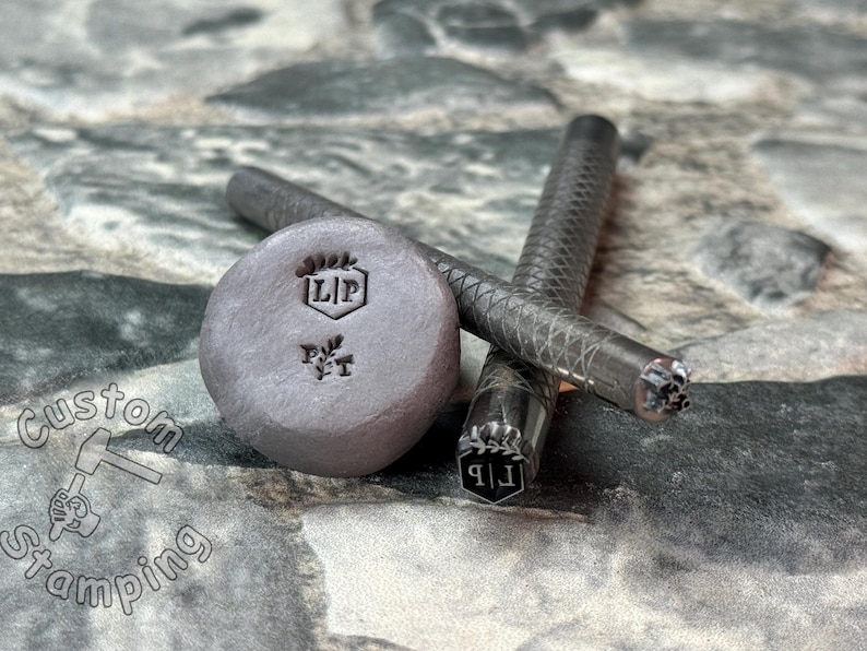 May include: Close-up of three metal stamps with the letters "LIP" and a small leaf design. The stamps are on a gray textured surface.
