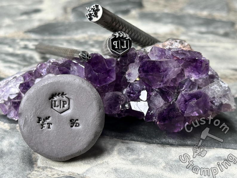 May include: A close-up of three metal stamps with different designs. The stamps are on a bed of purple amethyst crystals. The stamps are used for custom stamping.