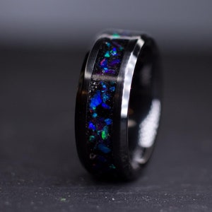 May include: A black tungsten carbide ring with a blue and green opal inlay.