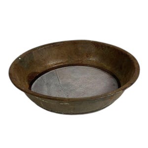 May include: A rusty, round metal sieve with a fine mesh screen. The sieve has a shallow, bowl-like shape and is likely used for sifting dry ingredients or straining liquids. The metal has a weathered appearance, suggesting age and use.