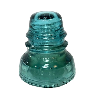 May include: A teal-colored glass insulator with a rounded top and a ridged design. The insulator has a flared base and a series of concentric rings. The text "No 20" is visible on the side. This antique piece is likely from a telephone or power line.