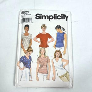 May include: A Simplicity sewing pattern envelope, number 8523, size Z 20, 22, 24. The white paper packaging features illustrations of six different top styles, including solid, striped, and patterned designs, with labels A through F for each.