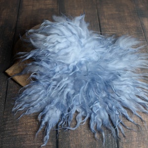 Peut inclure: Un tapis en fausse fourrure bleu clair avec une texture moelleuse. Le tapis est posé sur une surface en bois.