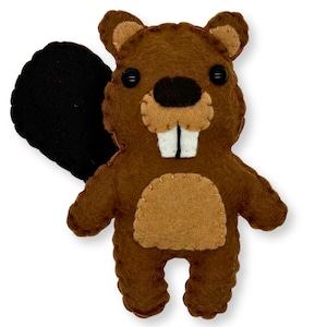 May include: A handmade brown felt beaver stuffed animal with a black tail. The beaver has tan accents on its belly, ears, and snout. Black button eyes and white felt teeth complete the design. A charming, handcrafted woodland creature.