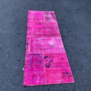 以下が含まれることがあります： ピンクと白のパッチワークの敷物で、花柄のデザインが施されています。敷物は、異なる布の切れ端を縫い合わせて作られています。