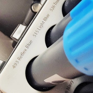 May include: Close-up of a set of black markers with color labels. The labels read "403 Reflex Blue", "515 Light Blue", "526 True Blue", "528 Navy", and "543 Mauve".