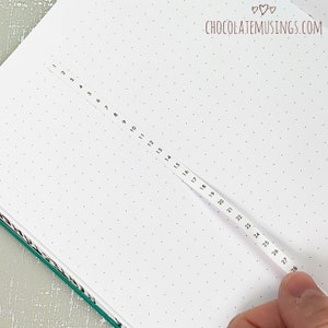 May include: A white page with a numbered ruler running down the center. The numbers on the ruler go from 1 to 28. The page is covered in small dots.