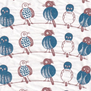 May include: A white fabric with a repeating pattern of blue and brown birds. The birds are stylised and have a simple design. The fabric has a subtle texture.