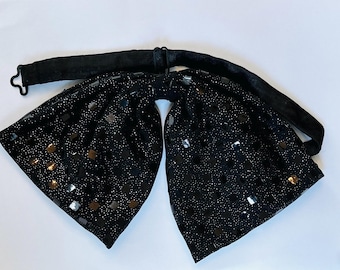 Könnte beinhalten: Eine schwarze Fliege mit einem glitzernden, quadratischen Muster. Die Fliege hat ein schwarzes Samtband.