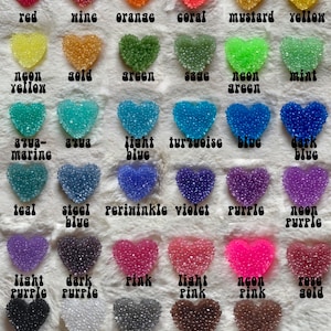 K&ouml;nnte beinhalten: Eine Tabelle mit 24 herzf&ouml;rmigen Harzst&uuml;cken in verschiedenen Farben, darunter Rot, Wein, Orange, Koralle, Senf, Gelb, Neon-Gelb, Gold, Gr&uuml;n, Salbei, Neon-Gr&uuml;n, Minze, Aquamarin, Aqua, Hellblau, T&uuml;rkis, Blau, Dunkelblau, Teal, Stahlblau, Periwinkle, Violett, Lila, Neon-Lila, Helllila, Dunkellila, Rosa, Hellrosa, Neon-Rosa, Ros&eacute;gold, Schwarz, Wei&szlig;, Silber, Braun und Kupfer.
