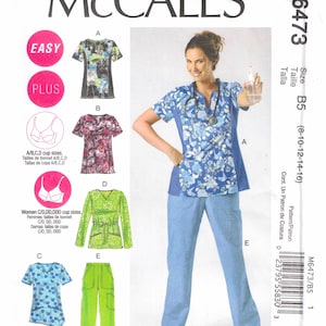 May include: McCall's sewing pattern M6473 for scrubs. The pattern includes options for tops and pants in various styles and sizes. The image shows a woman wearing a blue floral scrub top and light blue pants.