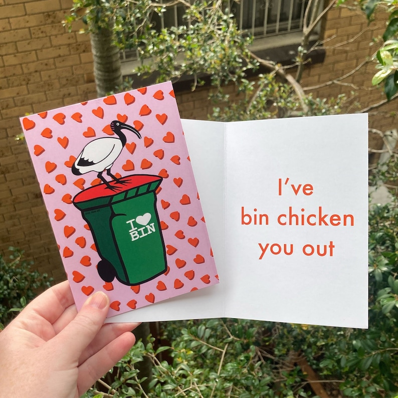 May include: A pink card featuring a white ibis bird perched on a green bin with a red heart and the words "I &hearts; BIN". The inside of the card reads "I've bin chicken you out" in orange.