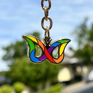 May include: A gold chain with a colourful butterfly charm. The butterfly is made of metal and has a rainbow design.