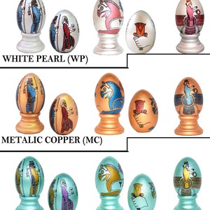 May include: Set of 12 decorative eggs with different designs, including a horse, a flower, and a person. The eggs are painted in various colors, including silver, white, copper, and turquoise. The eggs are displayed on stands.