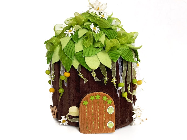 K&ouml;nnte beinhalten: Ein braunes Filz-Feenhaus mit einem gr&uuml;nen Filzdach, wei&szlig;en Filzblumen und einer braunen Filzt&uuml;r mit gr&uuml;nen Filzakzenten.