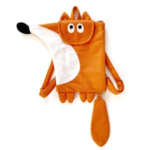 Op de afbeelding: Oranje rugzak in de vorm van een vos met witte vilt accenten en een lange staart. De rugzak heeft een ritssluiting en verstelbare banden.
