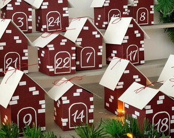 May include: A set of 18 small, red, cardboard houses with white numbers on the front. The houses are arranged in a pyramid shape, with the largest house at the bottom and the smallest house at the top. The houses are decorated with white paper and red ribbon.