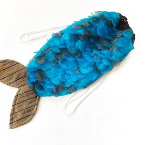 May include: A blue and brown mermaid tail costume with a blue tulle tail and brown fabric scales. The tail has a white string attached to it.