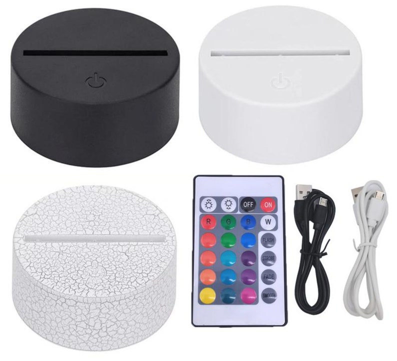 Op de afbeelding: Drie witte en zwarte ronde LED-nachtlampjes met een USB-kabel en een afstandsbediening met 16 kleurkeuzes. De afstandsbediening heeft knoppen voor aan, uit, flits, strobe, fade en smooth.