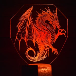 May include: A red dragon with wings outstretched is illuminated in an octagonal shaped lamp. The dragon is a detailed silhouette with a textured appearance.