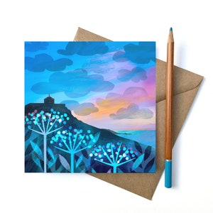 May include: A greeting card featuring a blue and purple sunset over a silhouette of a building on a hill. The foreground features three white flowers with blue centres.